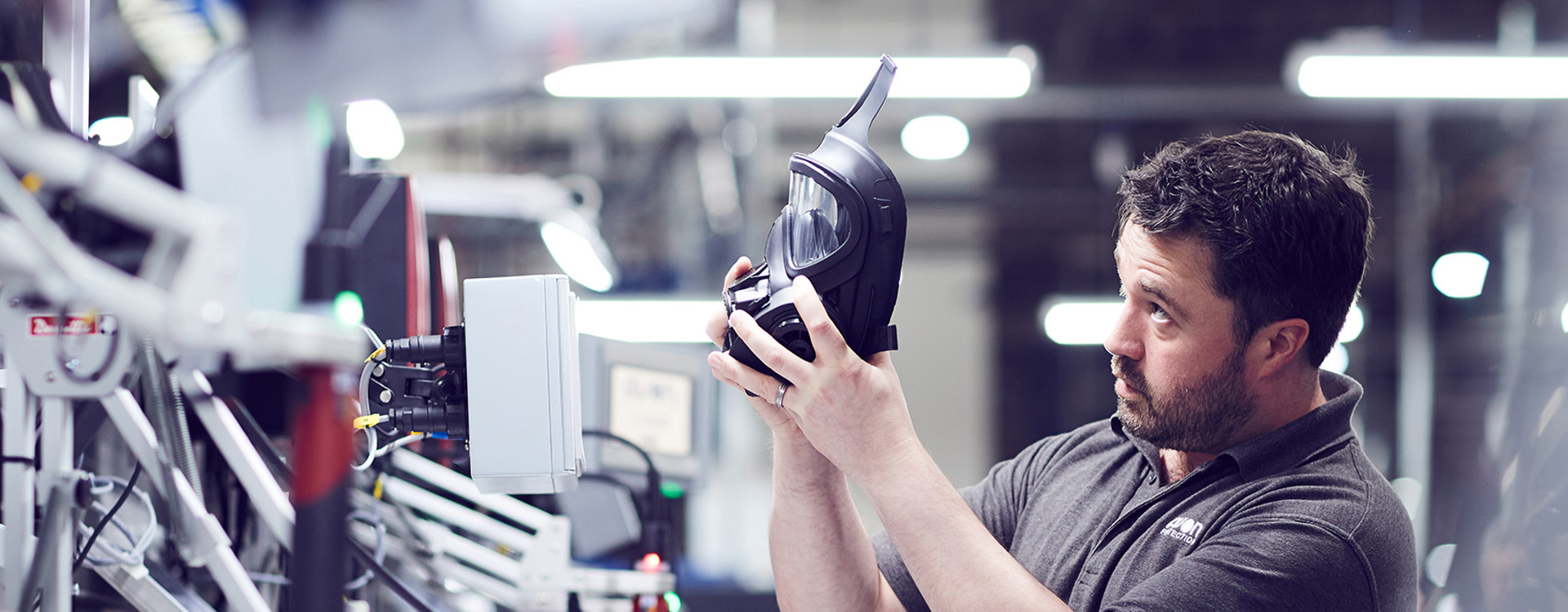 Male employee holding up an Avon Protection 50 series respirator to inspect