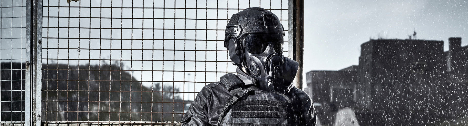 Soldier wearing a helmet and respirator guarding a fence