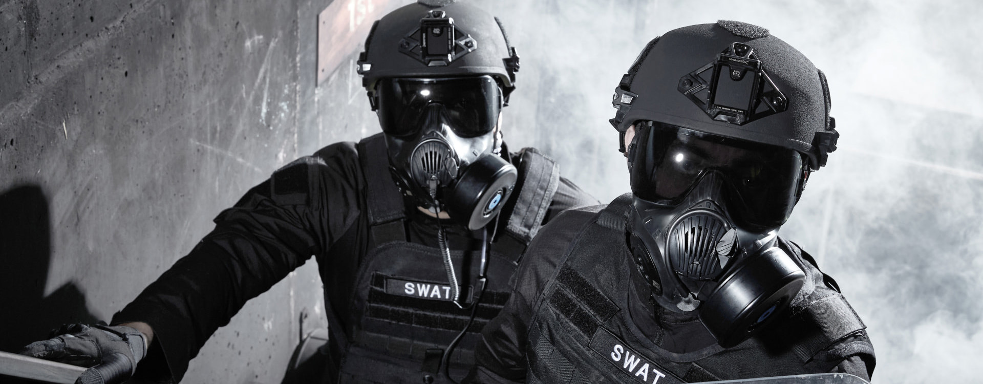 Two soldiers on staircase wearing ballistic helmets and respirators