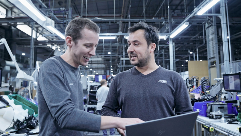 Engineering team collaborating on a laptop in a high-tech manufacturing facility for Avon Protection.