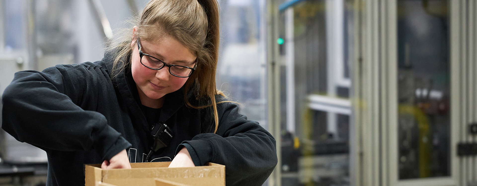 Female employee packing a box in a factory