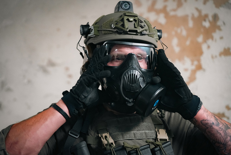 Tactical operator wearing an Avon Protection respirator and Team Wendy EXFIL helmet during a security simulation or tactical drill.