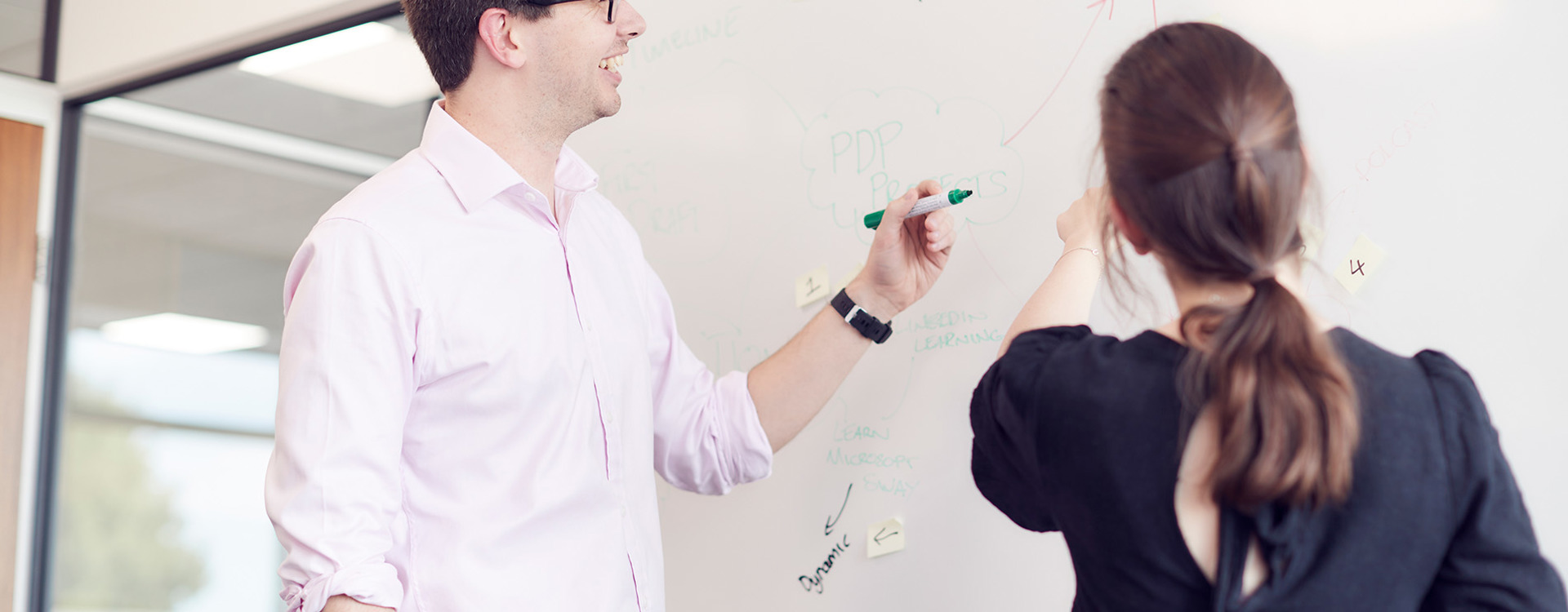 Male and female employee writing on a whiteboard