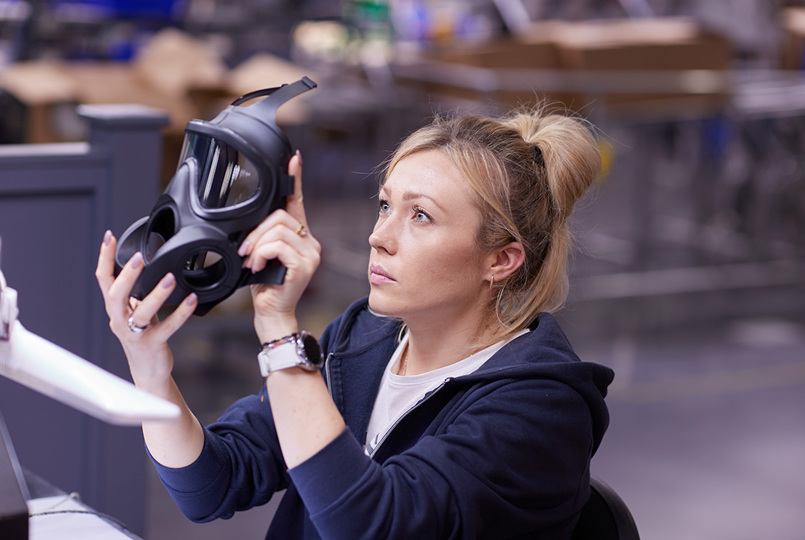 Employee holding an Avon Protection respirator up to the light to inspect