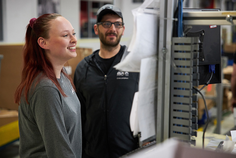 Two employees looking at a computer screen on a production line