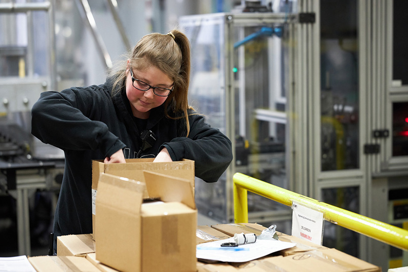 Female employee packing a box in a factory