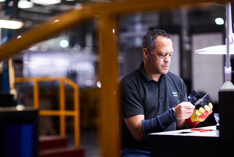 Male employee inspecting an Avon Protection respirator nose cup at a desk