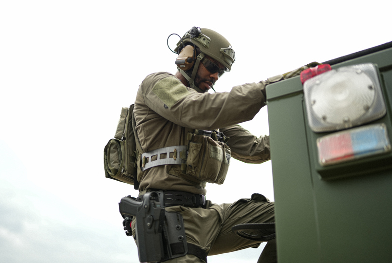 Tactical operator wearing a Team Wendy EXFIL helmet and ballistic vest mounting a specialized response vehicle.
