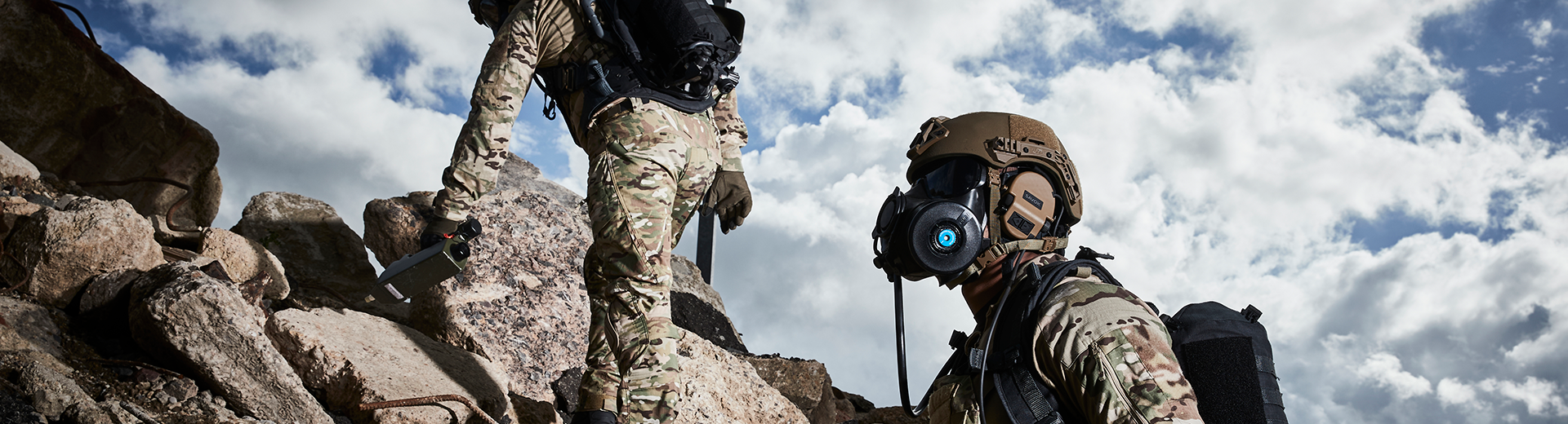 Two soldiers climbing a rubble pile wearing helmets and respirators