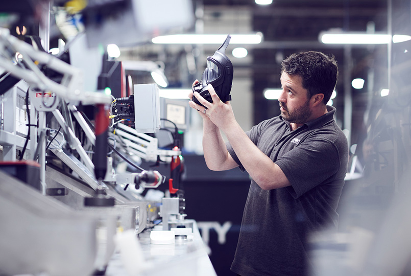 Male employee holding up an Avon Protection 50 series respirator to inspect